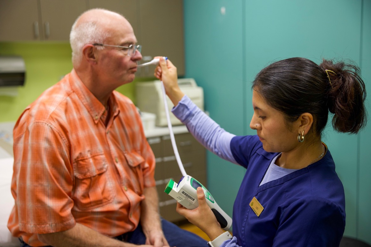 A medical assistant taking a patient's temperature.